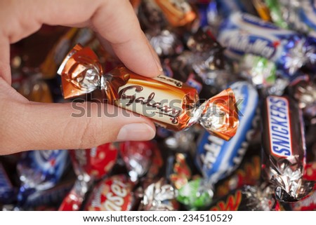 Paphos, Cyprus - December 19, 2013  Woman\'s hand holding Galaxy candy against background of candies manufactured by Mars, Incorporated. Studio shot.