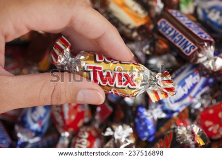 Paphos, Cyprus - December 19, 2013 Twix candy in woman\'s hand with background of Snickers, Mars, Twix, Milky Way, Galaxy, Bounty and Maltesers Teasers candies. All candies manufactured by Mars, Inc.