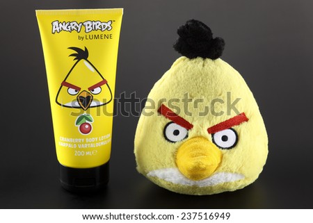 Tambov, Russian Federation - September 22, 2013 Yellow Angry Birds soft toy and Angry Birds by LUMENE Cranberry Body Lotion on black background.