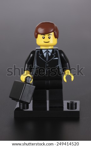 Tambov, Russian Federation - October 04, 2013 Lego businessman figure with black suitcase on black background.