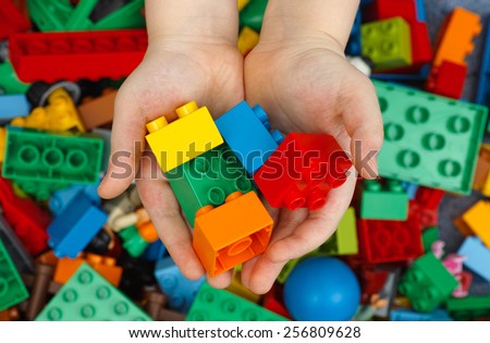 Tambov, Russian Federation - February 20, 2015 Lego Duplo Bricks in childs hands with Lego Duplo blocks background. Studio shot.