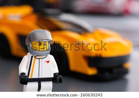 Tambov, Russian Federation - March 09, 2015 Lego McLaren P1 driver minifigure by LEGO Speed Champions and his car on background. Focus on the driver uniform. Studio shot.