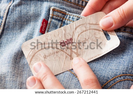 Tambov, Russian Federation - October 21, 2012 Woman\'s hand taking label logo with phrase \'Quality never goes out of style\' on the pair Levi\'s Jeans. Studio shot.