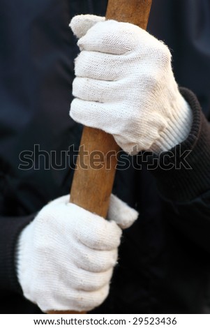 Human hands in white garden cotton gloves hold to handle of garden spade. Close-up