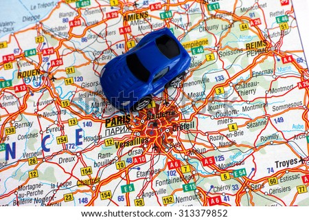 Blue car on map near inscription Paris, France.