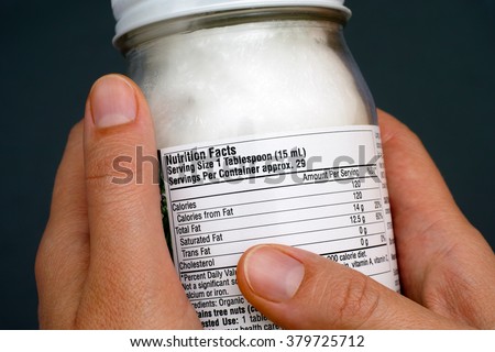 Reading a nutrition facts on organic coconut oil jar. Close-up.