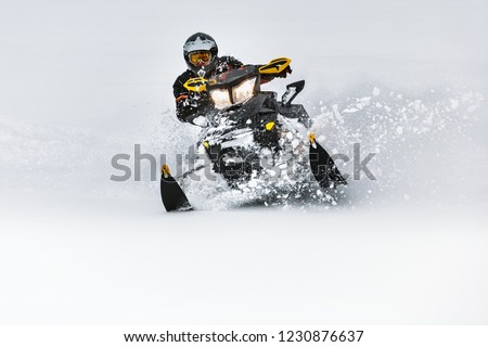 In deep snowdrift snowmobile rider make fast turn. Riding with fun in deep snow powder during backcountry tour. Extreme sport adventure, outdoor activity during winter holiday on ski mountain resort.