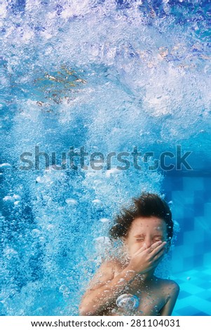 Amusing face portrait of smiling boy swimming and diving in blue pool with fun - jumping down underwater with splashes and foam. Family lifestyle and summer children water sports activity with parents