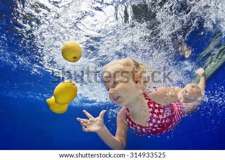 Children swimming lesson - little baby girl jump and dive underwater in pool with fun for lemon fruit. Active healthy lifestyle, water sports activity and exercising with parents on family vacation.