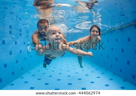 Happy full family - mother, father, baby son learn to swim, dive underwater with fun in pool to keep fit. Healthy lifestyle, active parent, people water sport activity, swimming lesson. Focus on child