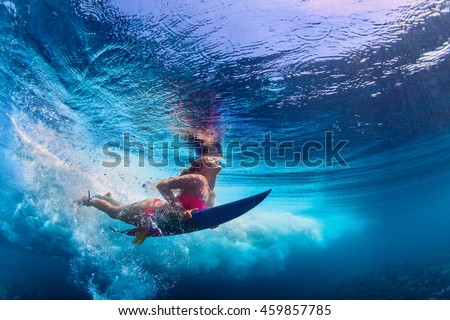 Young girl wearing bikini in action - surfer with surf board dive underwater under ocean wave. Family lifestyle, people water sport adventure camp and beach extreme swim on summer vacation with child.