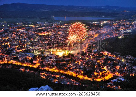 Night landscape of a city with street lights and fireworks flashing above.