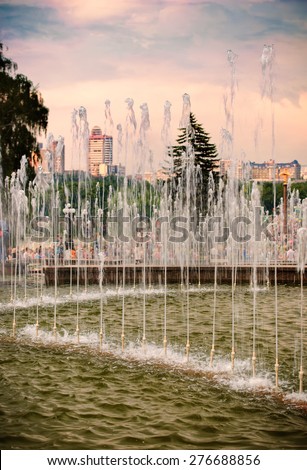 Water fountain on the city square in the background of the cloudy sunset sky
