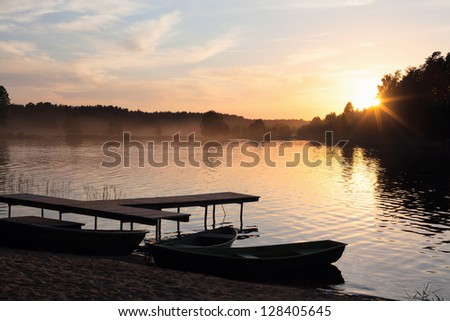 fog on the lake with boats in the evening