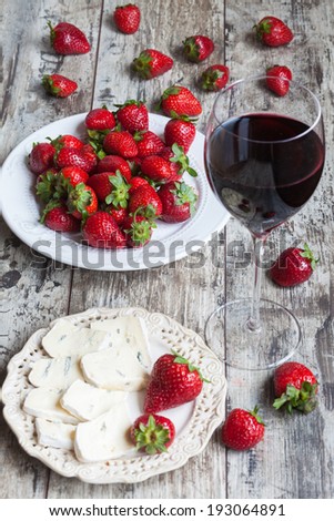 glass of wine, cheese and fresh strawberries on wooden table