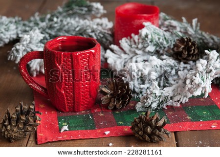 cup of tea, fir cones, fir branches in the snow, a candle on the wooden table