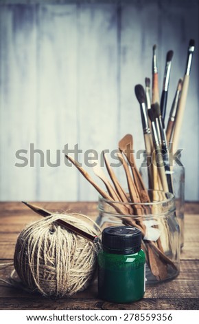 Green paint with art and craft tools on wooden background. Toned.