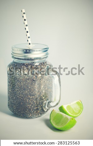 Refreshing chia seeds drink with water, coconut milk and lime in mason jar and white polka dot paper straw. Toned.