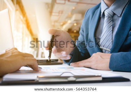two business executives sitting at desk discussing sales performance.