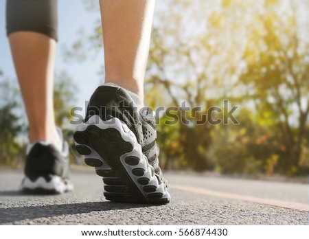 Athlete runner feet running on road closeup on shoe with nature background. woman fitness sunrise jog workout.