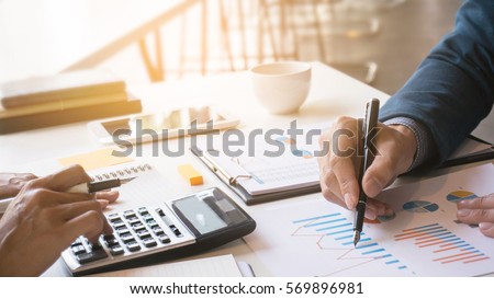 Business man analysis on data paper with business woman using calculator at the office