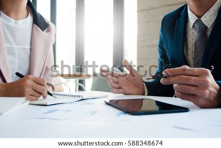 two business executives sitting at desk discussing sales performance at the office