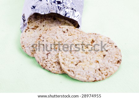 Rice cakes spilled from foil packaging on contrasting green background
