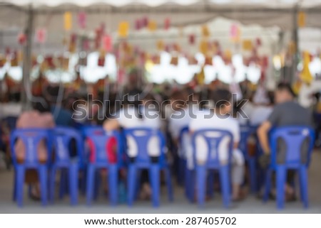 Defocus of people sit blue rubber chair opposite the monks and put holy thread on their head for merit in lampoon thailand temple pubic location