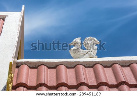 On the roof of thailand temple in the afternoon with lai thai bird statue with blue sky background