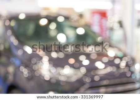 Blurry people meet at commercially cars stand in car shop