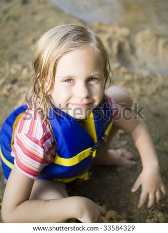 stock photo girl squatting on beach with life jacket on squatting girl