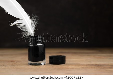quill pen and inkwell on wood table