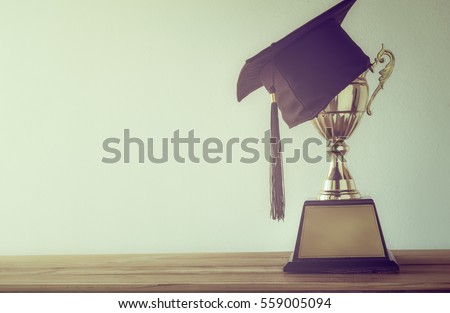 graduation cap with champion golden trophy on wood table with copy space ready for your design.graduation, success, education, concept