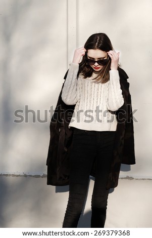 Full length portrait Fashionable Hipster girl standing against a white wall.