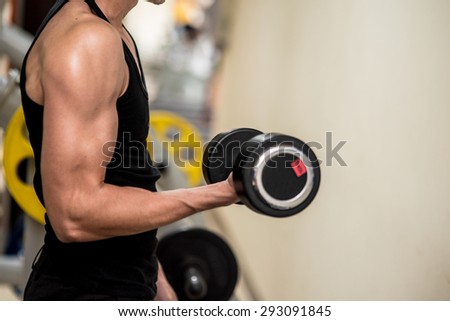 sport, bodybuilding, training and people concept , young man with dumbbell flexing muscles in Fitness Room.