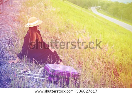 Women dressed in black with purple travel wallet,Traveling by road.