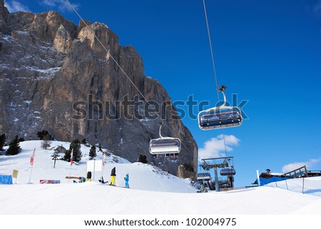 Ski lifts on background of rocks and ski trail in sunny day