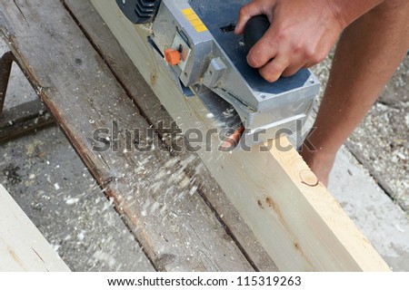 Carpenter with electric plane outdoors