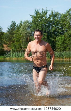 Happy strong man running on the water at beach in summer days