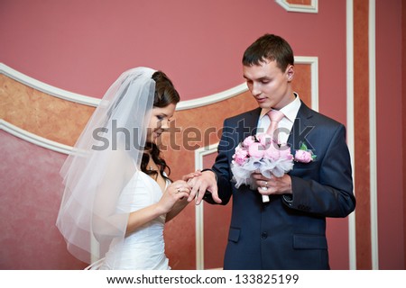 Beauty bride wears wedding ring on finger of elegant groom. Solemn registration of marriage.