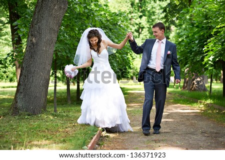 Happy bride and groom in shady alley on wedding walk