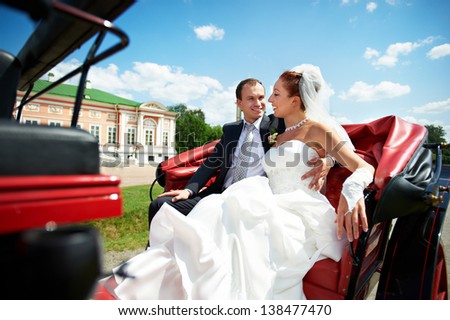 Happy bride and groom in beautiful carriage on wedding walk