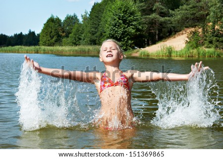 Little girl in water and spray on sunny day