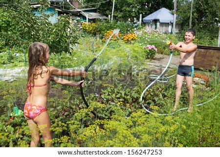Children play with garden hoses in summer day