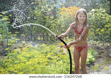Little girl playing with garden hose water
