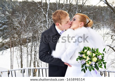 Romantic kiss happy bride and groom on winter wedding day