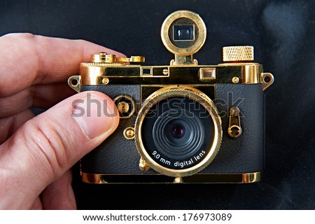 Mini gift golden camera in big hand closeup