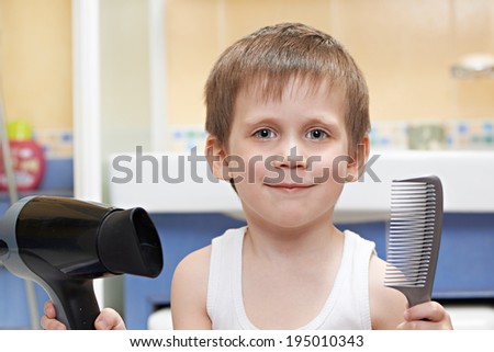 Little boy with a comb and hair dryer