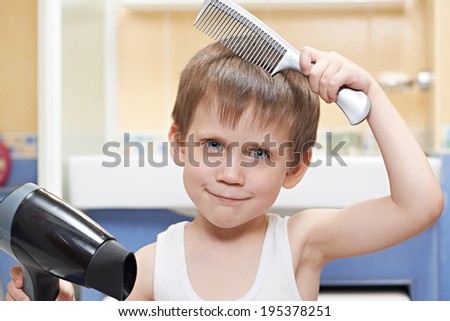 Little boy with a comb and hair dryer