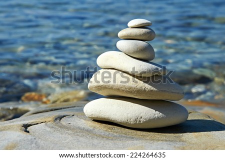Pyramid of stones zen balance in sea shore on sunny day